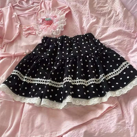 Dotted Doll Lace Skort arranged in a flat lay, showing the black polka-dot fabric, tiered shape, and contrasting white lace.