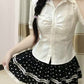 Model wearing the Dotted Doll Lace Skort with a fitted white button-up blouse while holding out the tiered hem.