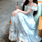 Model sitting on a chair with her feet on the seat wearing the midi version of the Ethereal Flower Princess Dress.