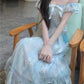 Model sitting with cross arms wearing the midi version of the Ethereal Flower Princess Dress.