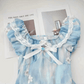 Detailed close-up of a flat lay of the mini Ethereal Flower Princess Dress, showcasing its lace trim, bow detailing, and floral embellishments.
