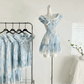 The mini Ethereal Flower Princess Dress on a mannequin next to a rack with the mini and midi versions of the dress hanging on it.