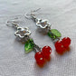 Angled view of the Fairy Cherry Pearl Earrings displayed flat with clear hook backing