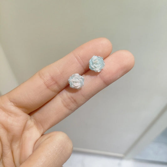 Delicate ombré rose earrings in soft blue and white hues, held gracefully in between two fingers from the Garden Party Pastel Earrings set.