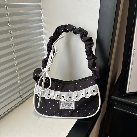 The Lacy Dotling Purse, a black polka-dot lace-trimmed purse, displayed on a white windowsill.