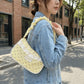 A model carrying the yellow Lace Dotling Purse, a polka-dot lace-trimmed purse, outdoors in a denim jacket.
