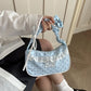 A model holding the light blue Lacy Dotling Purse, a polka-dot lace-trimmed purse, gathered by the handle.