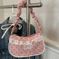 The Lacy Dotling Purse, a pink polka-dot lace-trimmed purse, hanging from a rack.