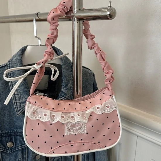 The Lacy Dotling Purse, a pink polka-dot lace-trimmed purse, hanging from a rack.