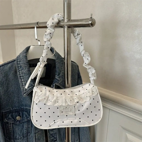 The Lacy Dotling Purse, a white polka-dot lace-trimmed purse, hanging from a rack.