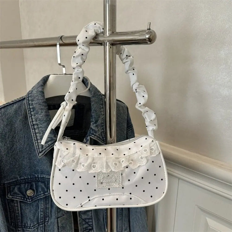The Lacy Dotling Purse, a white polka-dot lace-trimmed purse, hanging from a rack.