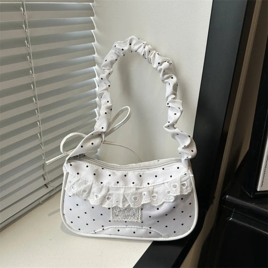 The Lacy Dotling Purse, a white polka-dot lace-trimmed purse, displayed on a white windowsill.