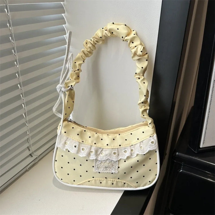 The Lacy Dotling Purse, a yellow, polka-dot, lace-trimmed purse, displayed on a white windowsill.