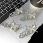 Four silver Liquid Metal Butterfly Hair Clips resting on a laptop keyboard.