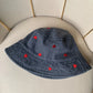 The Love Stitch Denim Bucket Hat in a black denim shade, showcasing the contrast of red hearts against the deep-colored fabric.