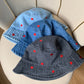 Different color variations of the Love Stitch Denim Bucket Hat arranged together, showing light and dark denim options with heart embroidery.