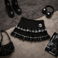 Flat lay of the Lovestruck Skull Skort styled with boots, headphones, and dark accessories.