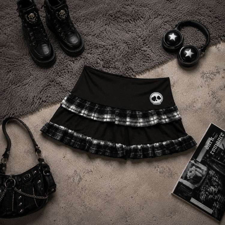 Flat lay of the Lovestruck Skull Skort styled with boots, headphones, and dark accessories.