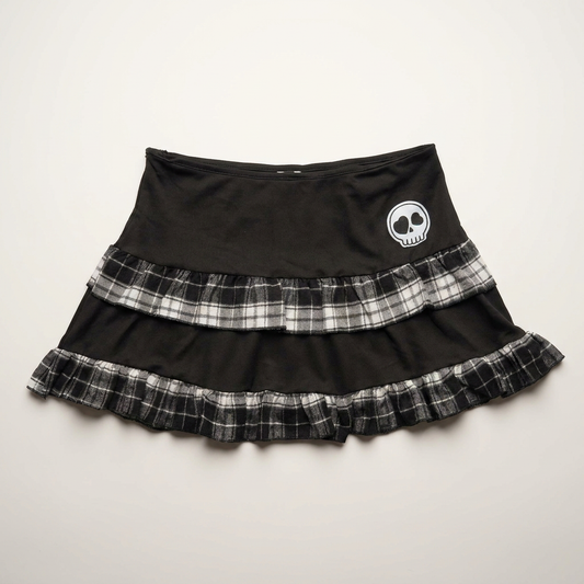 Front flat lay of the Lovestruck Skull Skort, featuring gray plaid trim and a heart-eyed skull patch.