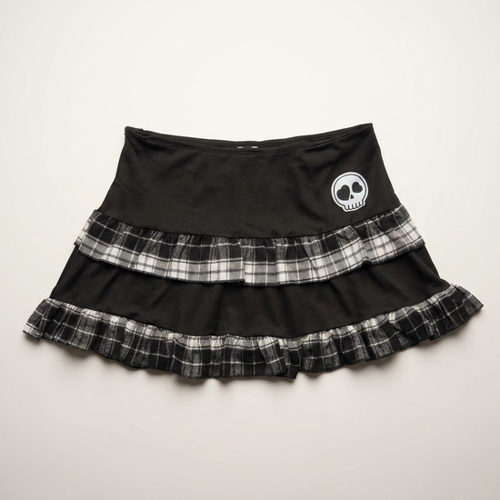 Front flat lay of the Lovestruck Skull Skort, featuring gray plaid trim and a heart-eyed skull patch.