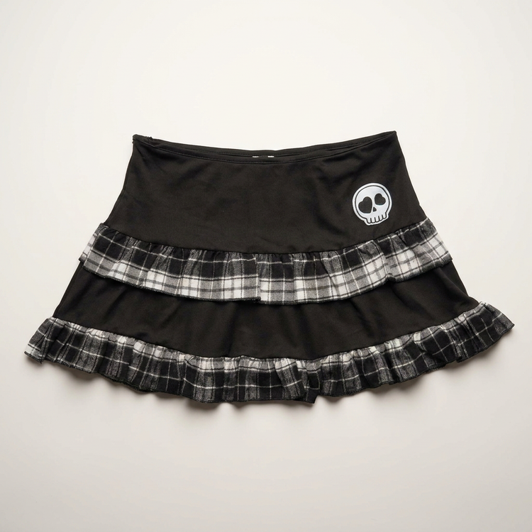Front flat lay of the Lovestruck Skull Skort, featuring gray plaid trim and a heart-eyed skull patch.