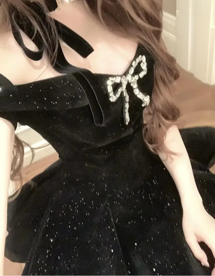 Close-up of the Midnight Gala Bow Dress, emphasizing the jeweled bow detail on black velvet off-shoulder dress.