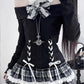 Close-up of the Midnight Manor Skort Set highlighting the faux two-piece sweater, corset-inspired lace-up front, black heart-shaped buttons, bow accents, and statement bow.