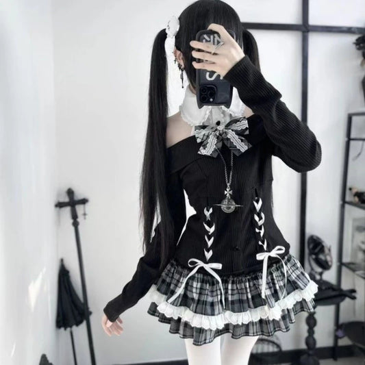 Model wearing the Midnight Manor Skort Set featuring a long-sleeve sweater with a faux layered design, halter off-the-shoulder neckline, corset-inspired lace-up front, black heart-shaped buttons, statement bow, and a plaid skort with built-in shorts.