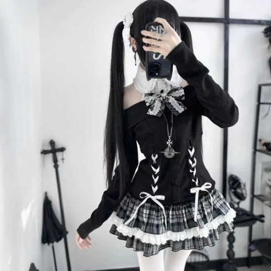 Model wearing the Midnight Manor Skort Set featuring a long-sleeve sweater with a faux layered design, halter off-the-shoulder neckline, corset-inspired lace-up front, black heart-shaped buttons, statement bow, and a plaid skort with built-in shorts.