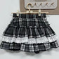 The layered plaid skort from the Midnight Manor Skort Set featuring built-in shorts and a comfortable elastic waistband on a hanger.