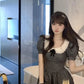 Model standing in bathroom lighting wearing the Midnight Mourning Baby Doll Dress with full silhouette on display