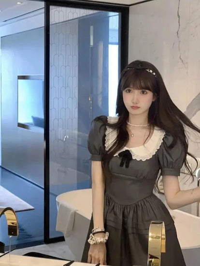 Model standing in bathroom lighting wearing the Midnight Mourning Baby Doll Dress with full silhouette on display