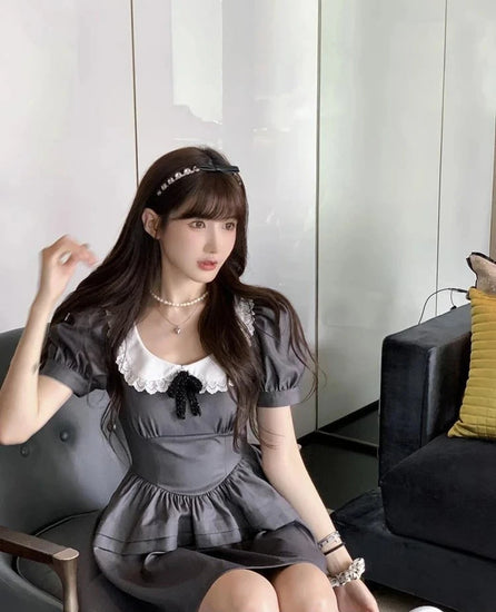 Model sitting down wearing the Midnight Mourning Baby Doll Dress, showing the lace collar and puff sleeves