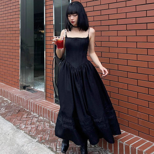 Model standing in front of a brick wall wearing the Midnight Sonata Corset Dress, showing the corset-inspired panel seaming  and flowing skirt.