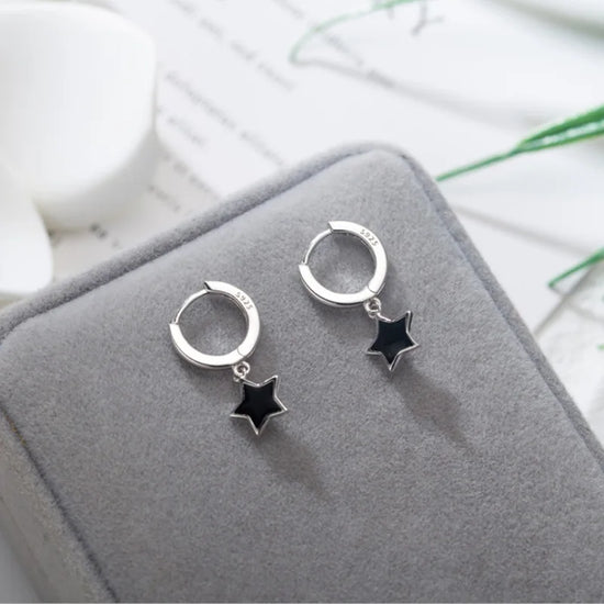 The Midnight Star Drop Earrings, black star drop earrings, arranged on a gray velvet jewelry box.
