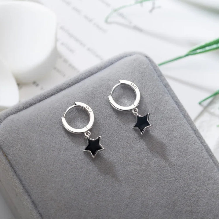The Midnight Star Drop Earrings, black star drop earrings, arranged on a gray velvet jewelry box.