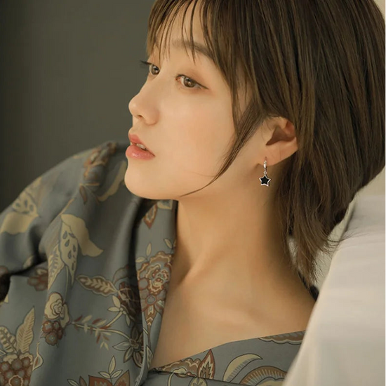 A model wearing the Midnight Star Drop Earrings in warm lighting.