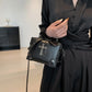 Moonlit Mourning Crossbody carried by the top handle with the cross design.
