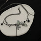 The Moonvine Dragonfly Necklace displayed on a black background, highlighting the dark silver finish and elegant gemstone accents.