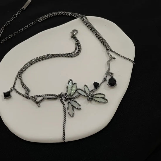 The Moonvine Dragonfly Necklace displayed on a black background, highlighting the dark silver finish and elegant gemstone accents.