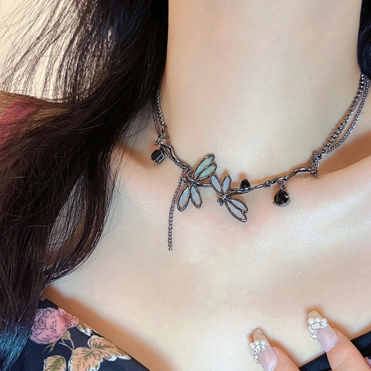 The Moonvine Dragonfly Necklace styled with a dark floral top, showcasing the delicate dragonfly details and smoky silver tones.
