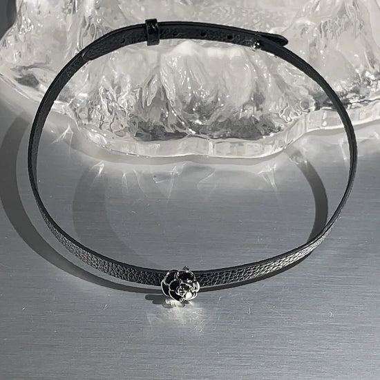 Black faux leather choker with rose centerpiece detail.