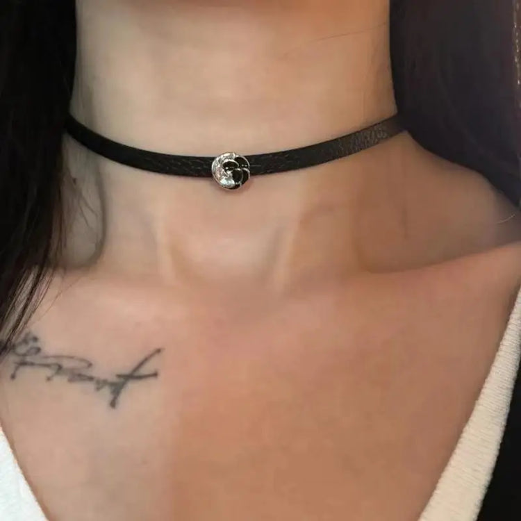 Minimal black choker with silver rose charm styled on neckline.
