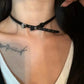 Model wearing the Obsidian Grace Rose Choker with silver rose detail on a black strap.