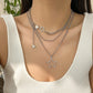 The layered silver star Orbit Dreams Necklace worn with a white ribbed tank top.