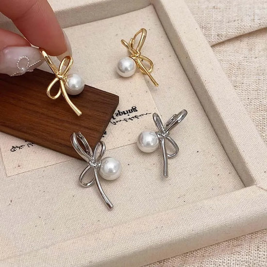 Gold and Silver Pearl Whim Bow Earrings displayed together in a box