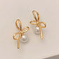 Gold Pearl Whim Bow Earrings displayed on white surface