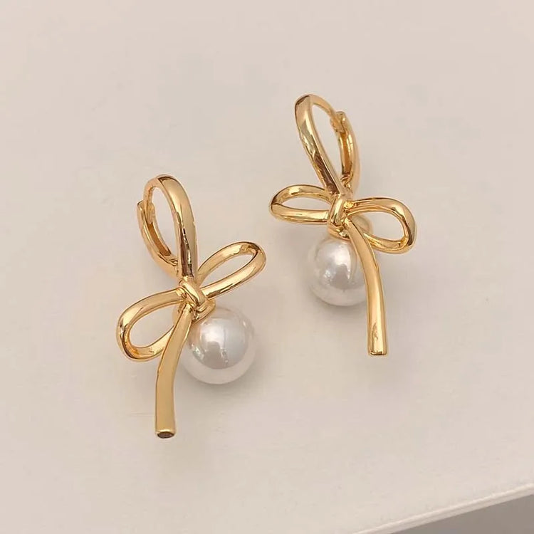 Gold Pearl Whim Bow Earrings displayed on white surface