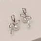Silver Pearl Whim Bow Earrings displayed on white surface
