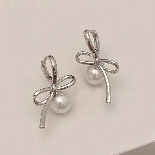 Silver Pearl Whim Bow Earrings displayed on white surface